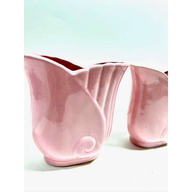 A graceful pair of vintage ceramic vases featuring a soft blush pink glaze and sculptural fluted silhouette inspired by...