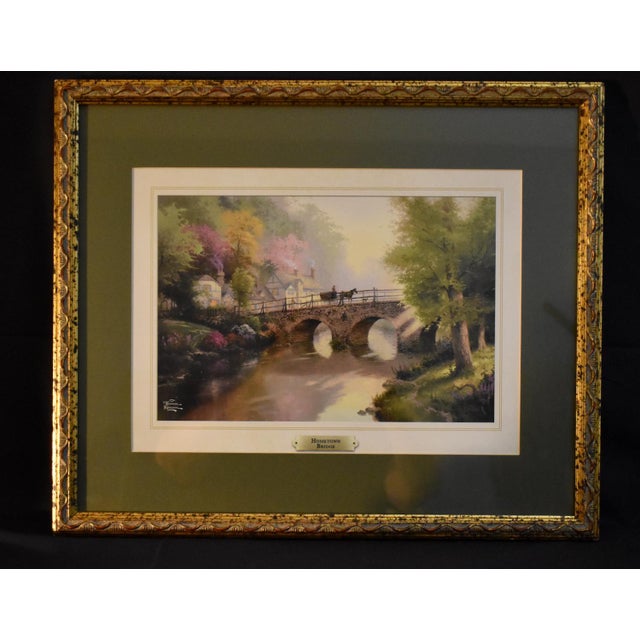 Vintage (1990's) Lithograph from Thomas Kincaid. "Hometown Bridge" Theme. Print is dbl. Mated with a Gold Wood Frame. The...