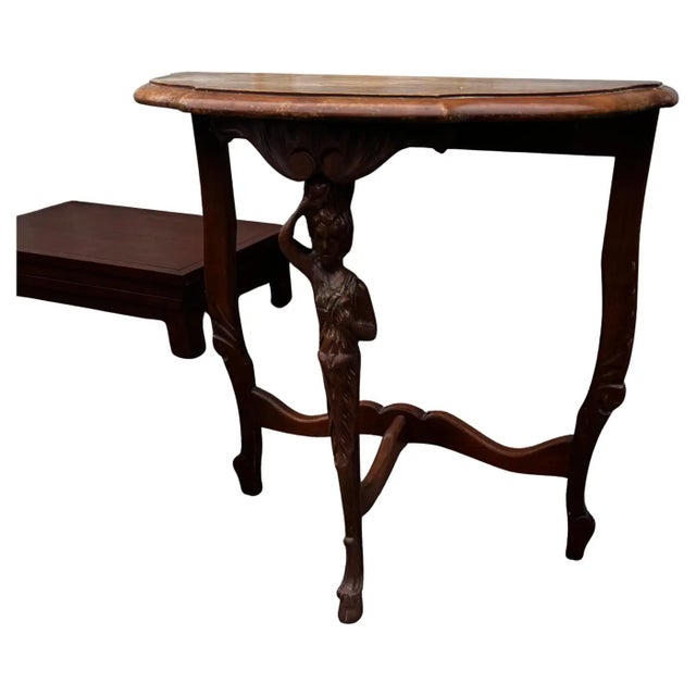 This table was made around the turn of the century. It has a beautifully carved lady on the fore leg. The top is demilune...