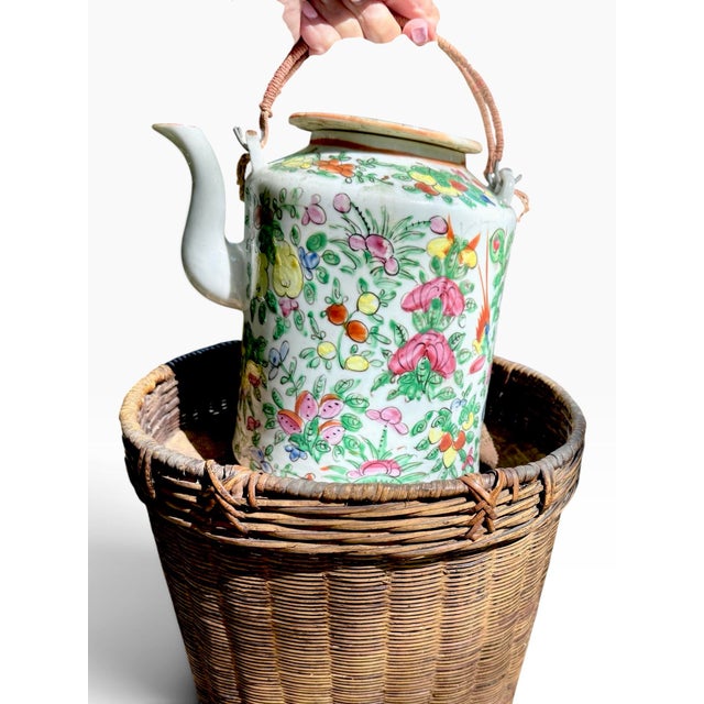 An antique Chinese famille rose porcelain teapot, circa 1890 - 1900, with its fitted woven warming basket and padded...