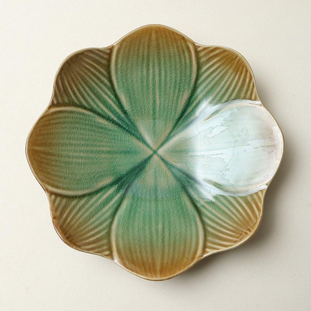 A pair of irregular ceramic plates featuring a gradient green-to-brown "ice-crack" (crackle) glaze; a delicate network of...