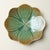 A pair of irregular ceramic plates featuring a gradient green-to-brown "ice-crack" (crackle) glaze; a delicate network of...
