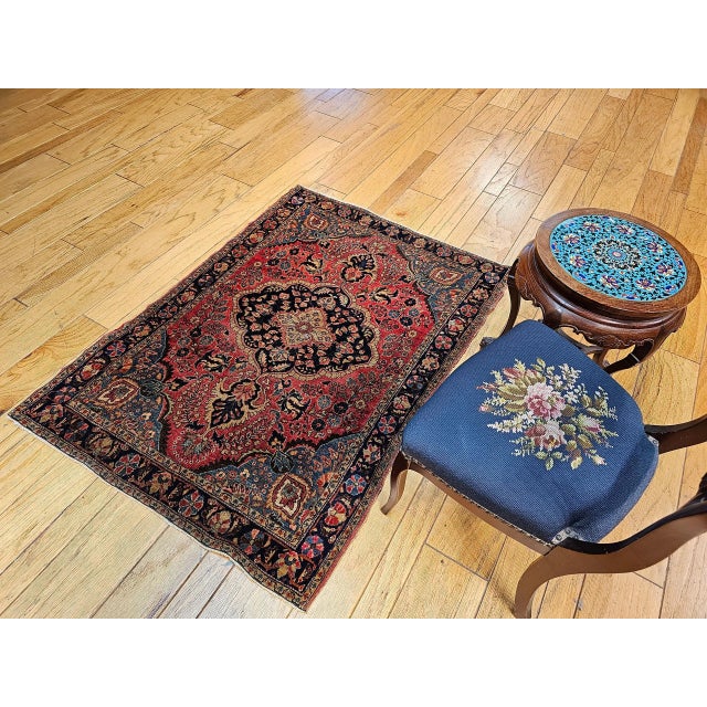A wonderful small Sarouk area rug from the 1st quarter of the 1900s. The rug has a floral design set in a red color field...
