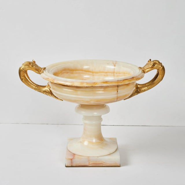 An elegant pair of hand carved and polished onyx tazzas in the Empire style with gilded bronze mounts.