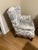 “Classic wingback accent chair upholstered in timeless blue-and-white toile fabric featuring pastoral French country...