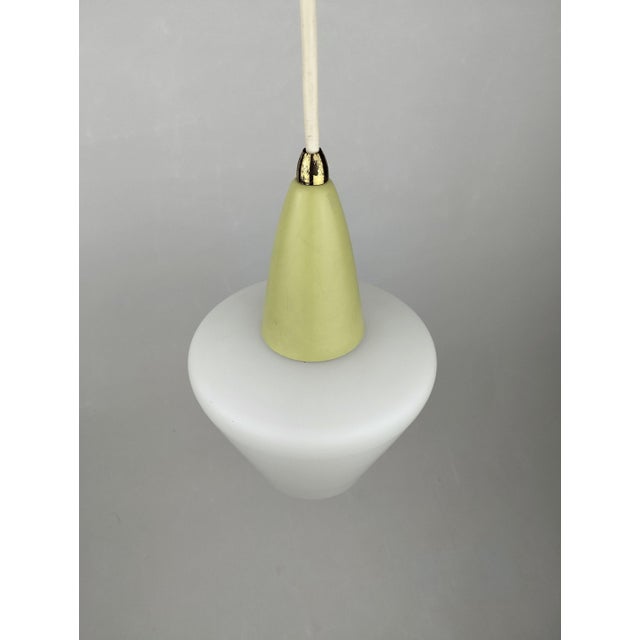 This charming little pendant lamp from the 1950s consists of a conical, matte white opal glass shade and a pastel green...