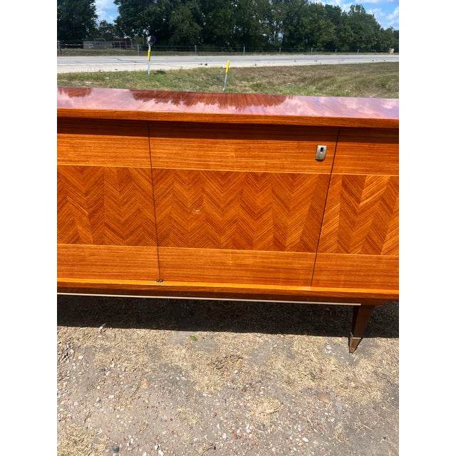 A sophisticated French Art Deco sideboard, circa 1940, showcasing richly figured light Macassar veneer with an elegant...
