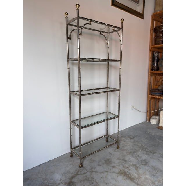 Elegant Hollywood Regency style five-tier étagère bookcase crafted in faux bamboo chrome with brass accents. The tall,...