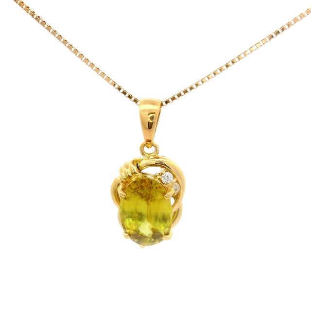 A striking pendant necklace featuring a 2.79-carat oval sphene with a vibrant green hue. The sphene is elegantly...