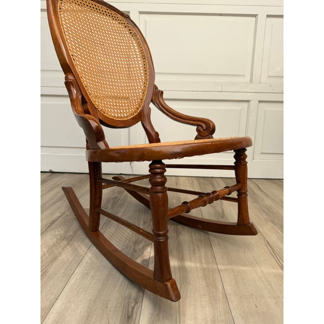 Here is a beautiful antique Victorian rocking chair dating to approximately 1890–1910, featuring a carved wood frame with...