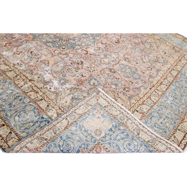 Beautiful vintage Persian distressed hand-knotted wool rug with a rose color field. This piece has a blue frame and...