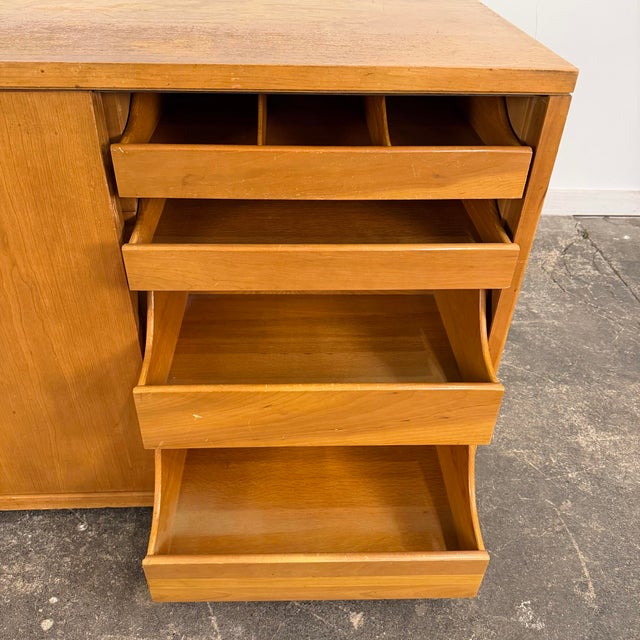 Mid Century John Widdicomb sideboard or storage chest with sliding doors. The sliding doors feature recessed oval-shaped...