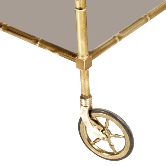 This art deco bar cart features a structure of bamboo shaped gilt brass with a smoked glass top.