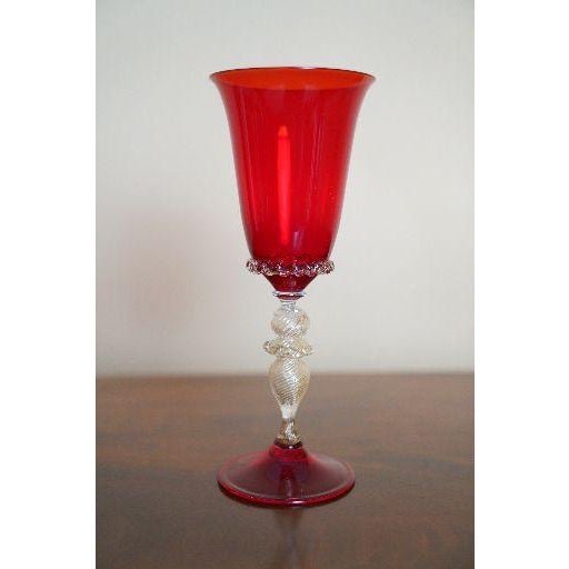 A striking vintage Murano art glass chalice featuring a ruby red flared cup, matching red foot, and sculptural clear glass...