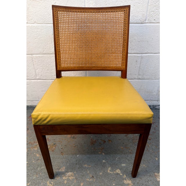 Set of six Mid-Century Modern walnut dining chairs featuring woven cane backrests and vibrant yellow vinyl upholstered...