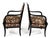 A pair of French-style armchairs featuring an ebonized wood frame with carved dolphin arm supports. The chairs have a...