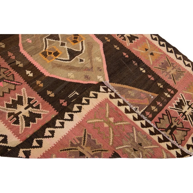 Beautiful vintage Turkish Kilim hand-knotted wool runner with a brown field. This rug has a beige frame and multicolor...