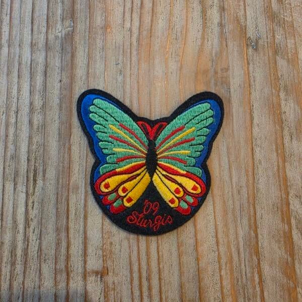 A sophisticated 12-piece assembly of motorcycle rally artifacts, headlined by the colorful 2009 Sturgis Butterfly and a...