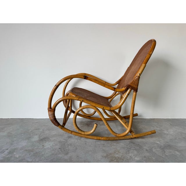 Embrace timeless craftsmanship with this vintage bamboo and cane rocking chair, inspired by the classic Thonet style....