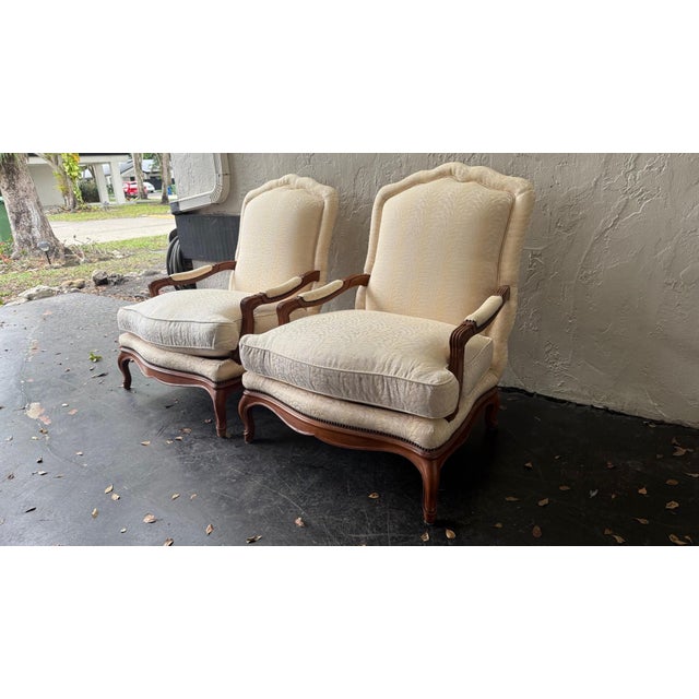 A rare and gorgeous pair of French Provincial Louis XV-style upholstered lounge chairs, crafted by Baker Furniture in the...