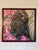 This artwork features a close-up of a bison's head, set against a vibrant backdrop of pink blossoms that evoke a sense of...