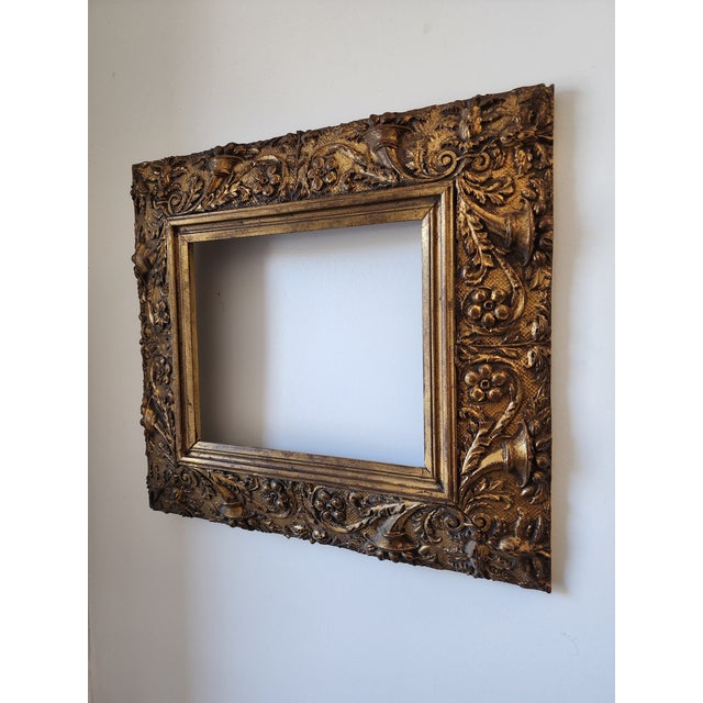 A high-quality antique baroque/rococo style frame carved from gold gilt wood. It features detailed design elements of...