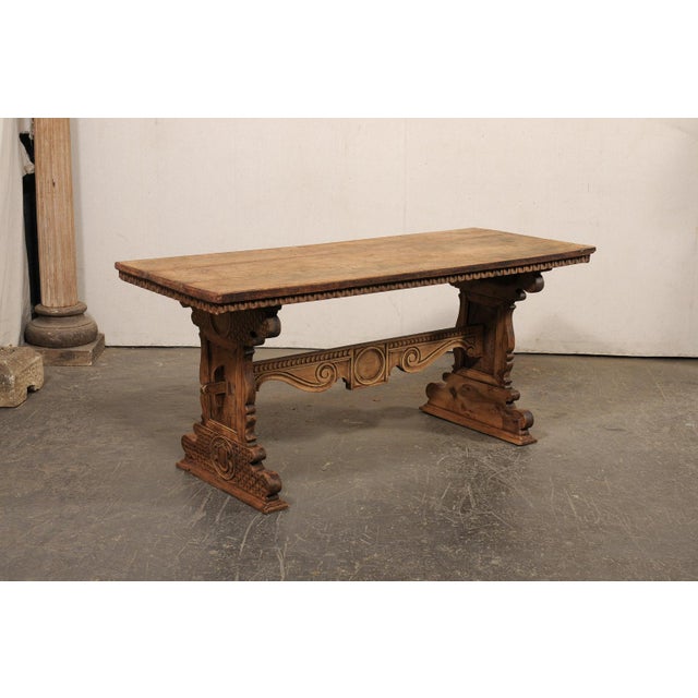 A finely-carved Italian wood trestle table from the 18th century. This antique table from Italy has been meticulously...