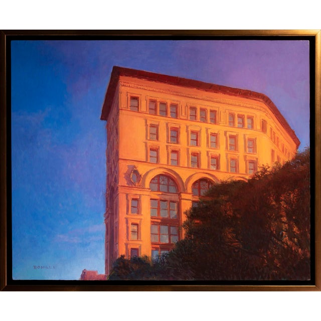This oil on panel artwork captures a striking architectural structure bathed in warm, golden light against a vibrant blue...