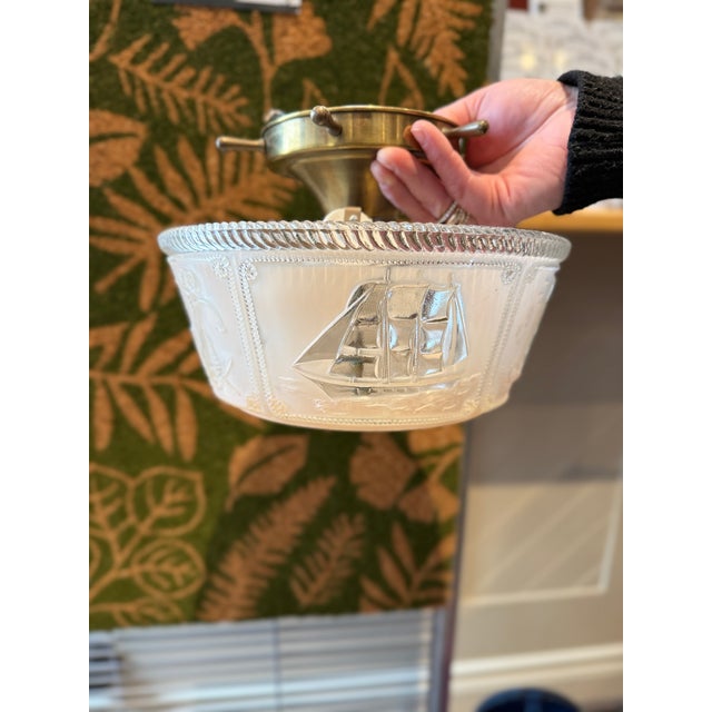 A striking 1950s nautical-themed ceiling light fixture featuring a beautifully detailed frosted glass shade embossed with...