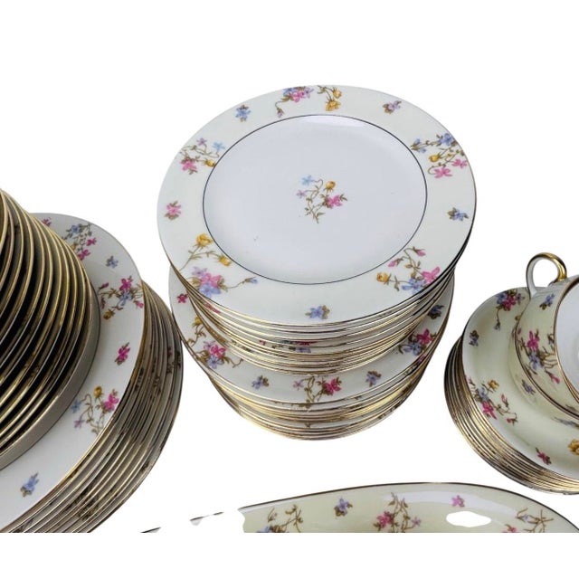 French porcelain partial dinner service by J.P. Limoges, decorated with a polychrome floral vine pattern and gilt trim....
