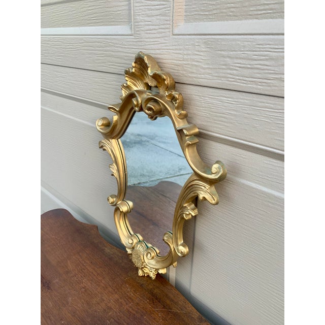 An Italian Rococo–style giltwood wall mirror, richly carved with scrolling acanthus and shell motifs that give the piece...