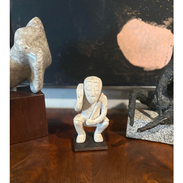 Stone carved figure of a monkey holding a stick. Mounted to a metal base. Standing 8” high X 6”’wide X 3” deep. In...