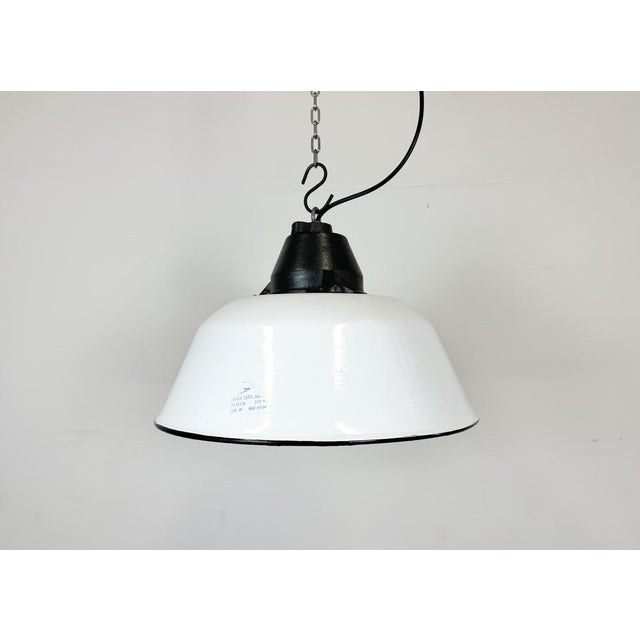 Industrial hanging lamp manufactured by Szarvasi Vas - Fém in Hungary during the 1960s. It features a white enamel shade...