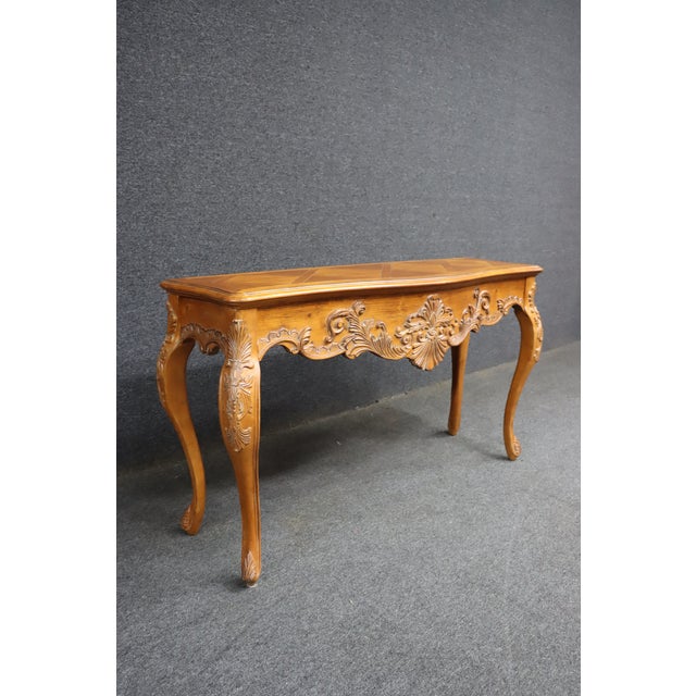 Classic Ethan Allen console in the Country French style, crafted in pine with a shaped top and detailed carved apron. The...
