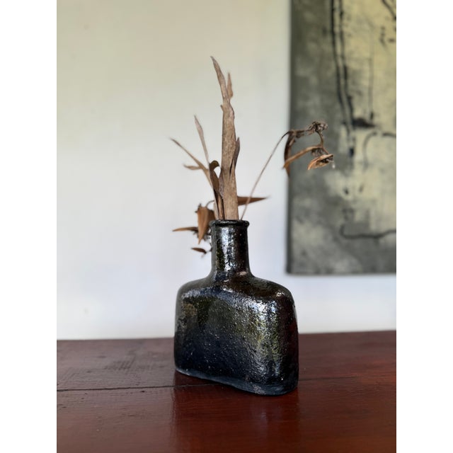 A sculptural handcrafted ceramic vase defined by its compact architectural silhouette and richly glazed surface. The form...