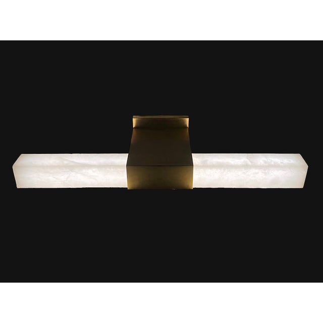Rectangular bars of natural alabaster flank a squared antique-burnished brass bracket on this Visual Comfort 24-inch Over...