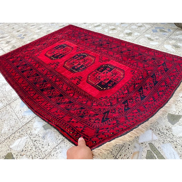 This bold Turkmen Bokhara rug features three repeating octagonal medallions, known as "guls," rendered in deep indigo...