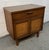 Stylish mid-century modern cabinet/nightstand featuring a warm walnut finish, clean lines, and woven cane-front double...