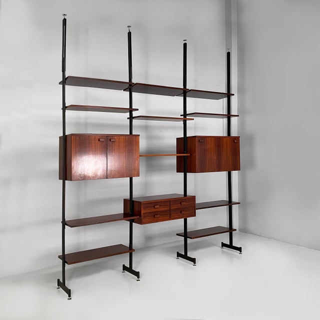 Italian mid-century modern modular bookcase in wood and metal, 1960s Modular ceiling-floor bookcase in wood. It features...