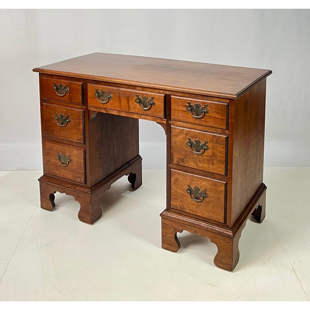 A Chippendale style solid walnut kneehole desk featuring an arrangement of seven dovetailed drawers and tall straight...