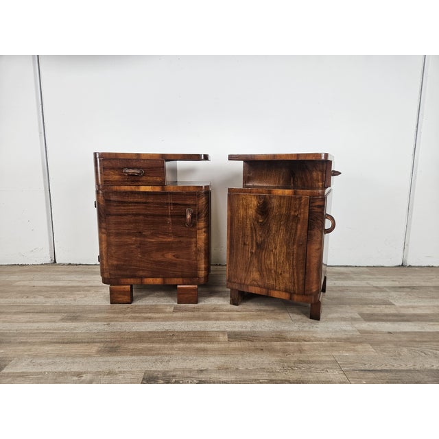 A pair of 1940s Art Deco bedside tables clad in walnut burl, distinctive for their compact size and elegant, slightly...