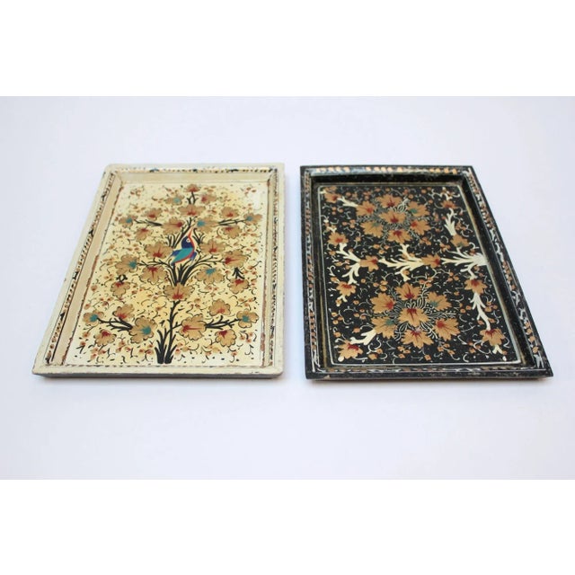 Set of two hand-painted/decorated trays (ca. 1970s, India). The cream and gold tray depicts a bird with pops of red and...