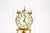 A brass German 400-day anniversary clock under a glass dome with a spired brass finial crown, white enamel dial with...