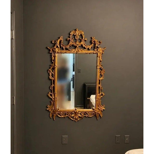 Striking vintage gilt wall mirror with an elaborate Rococo and Chinese Chippendale-inspired silhouette. The sculptural...