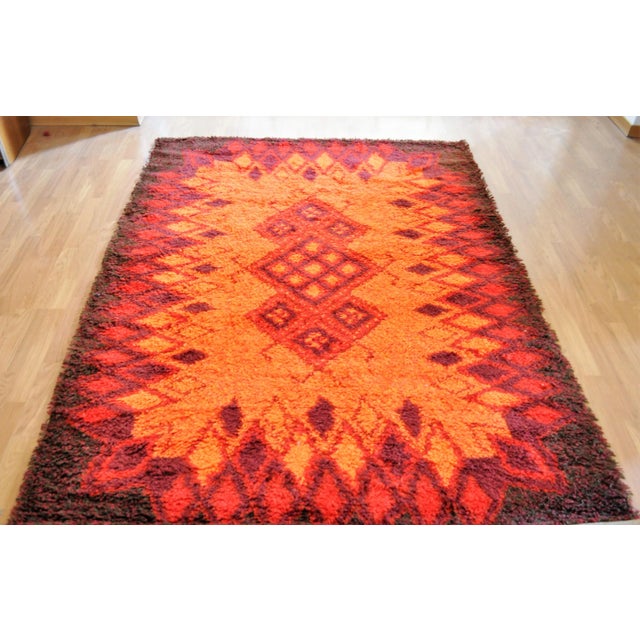 This rug in brown, orange, and red colors was made in Italy in the 1970s.