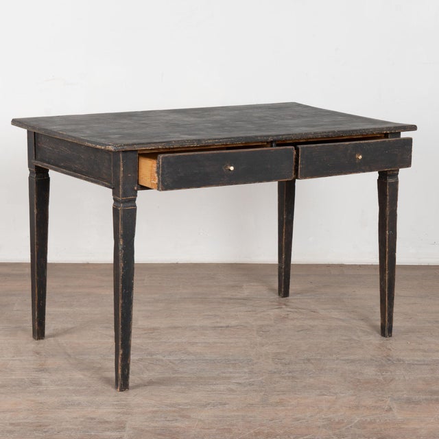 Late 19th century Swedish table crafted in pine and fitted with two drawers. The table stands on tapered legs and features...