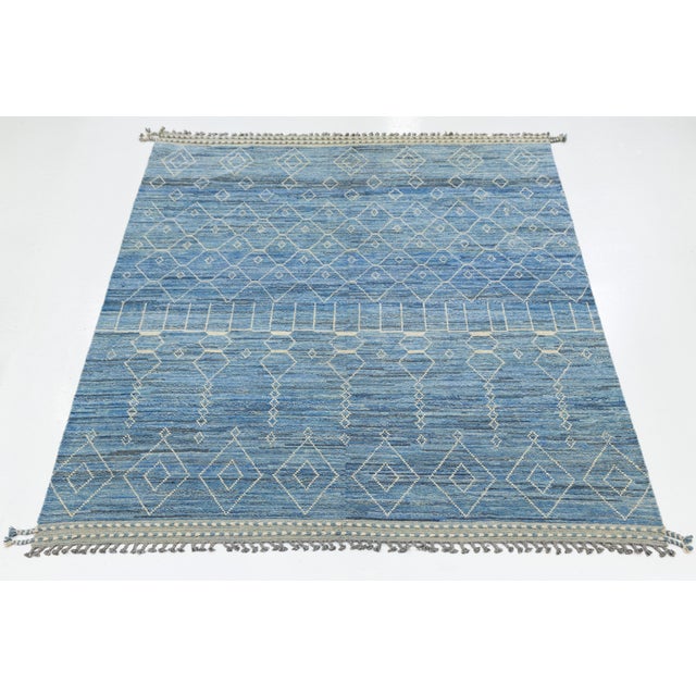 This modern wool rug features a striking interplay of white geometric motifs across a rich blue gradient field. The...