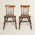 A stunning pair of early 19th century English elmwood side chairs, each with solid elm seats supported by turned legs and...