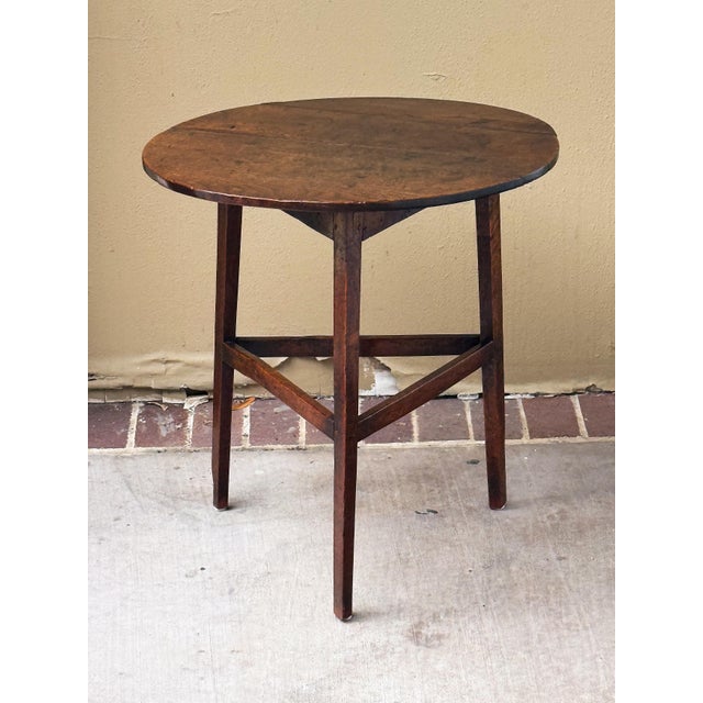 A handsome period English cricket table of patinated oak from the Georgian Era, c.1790, featuring the traditional round or...