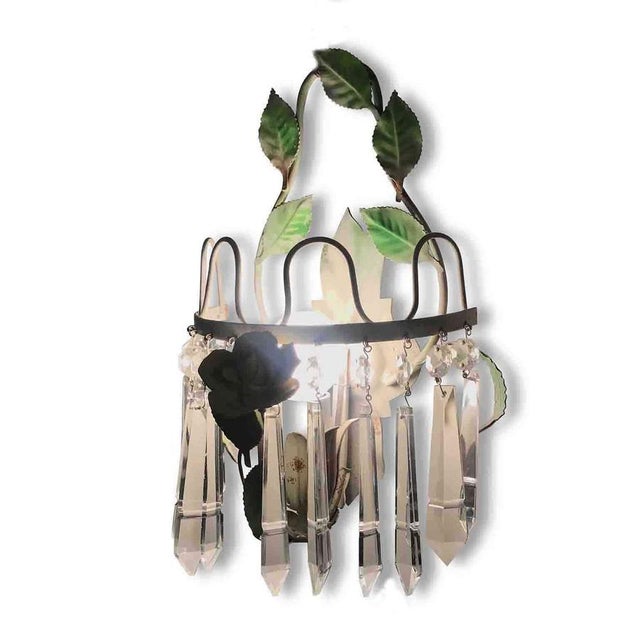 Pair of 1970s Green Lacquered Iron and Crystal Sconces with Porcelain Roses, this single-light pair of wall lights is in...